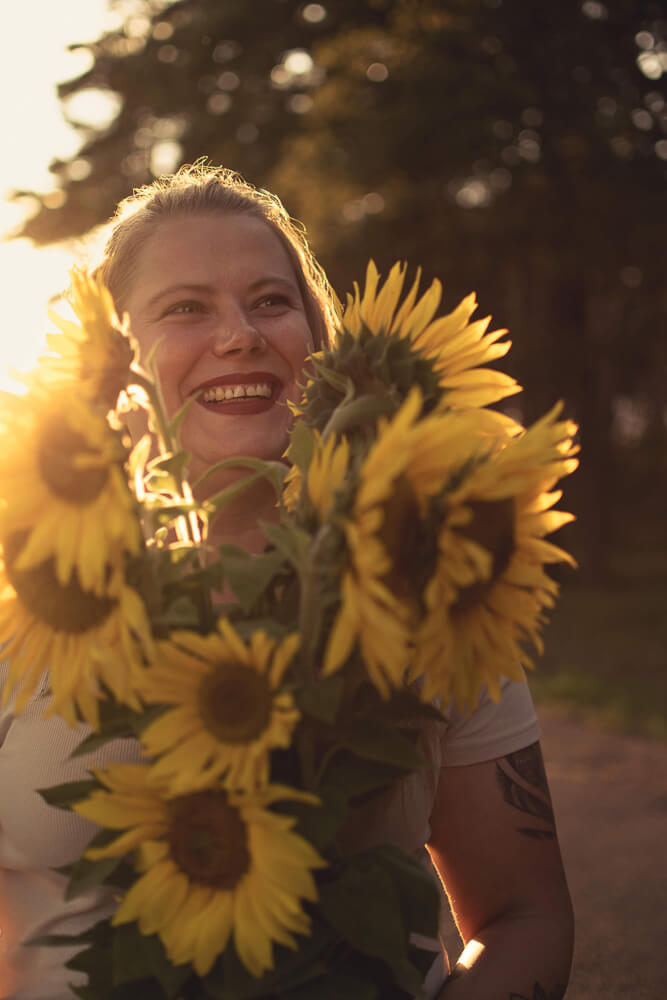 Portrait Frau mit Sonnenblumen in der Hand und Sonnenuntergang