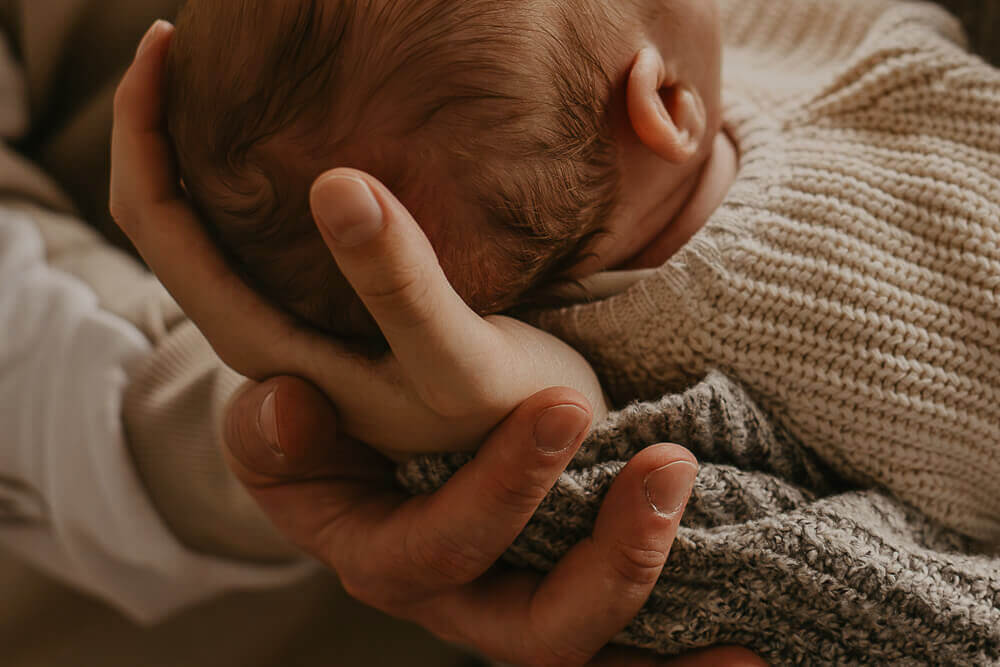 Elternhände halten Babykopf