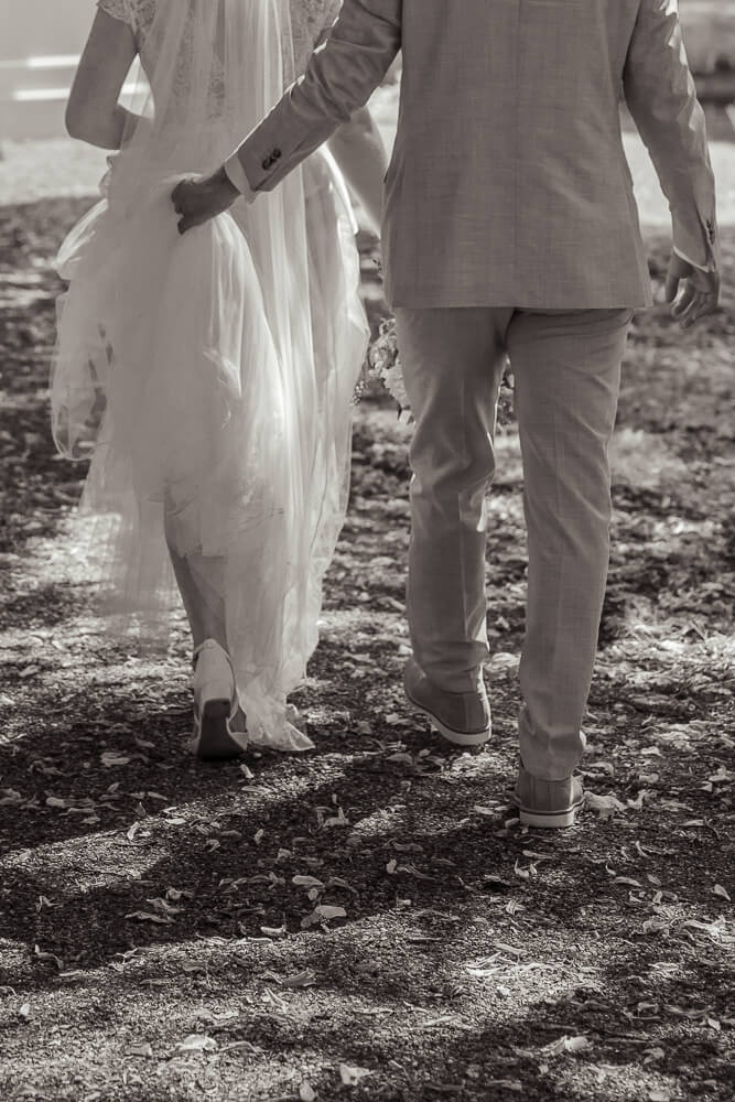 Bräutigam hält das Kleid seiner Braut damit es nicht dreckig wird